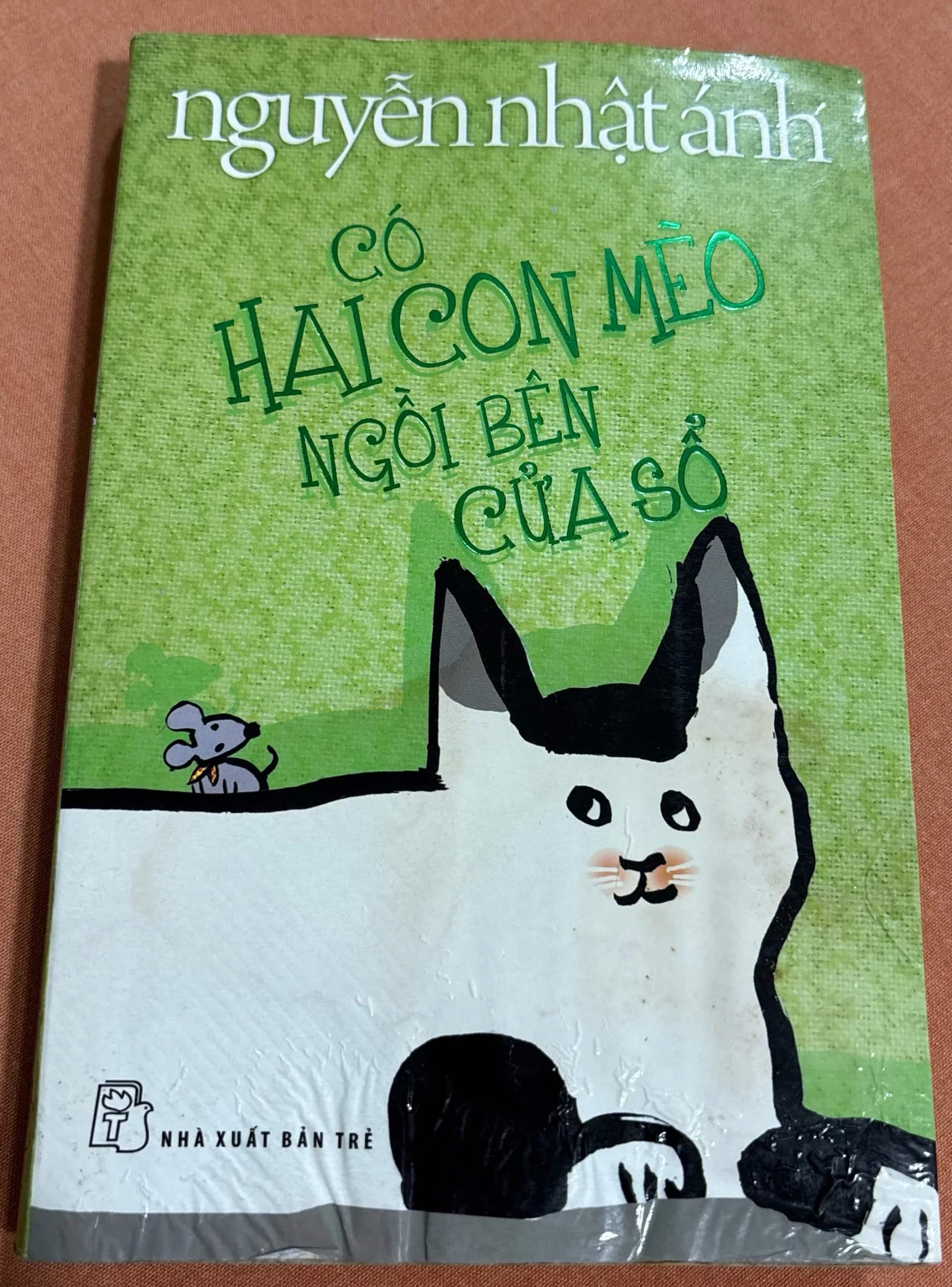 Có hai con mèo ngồi bên cửa sổ